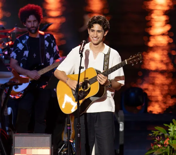 A guitar player smiles on stage.
