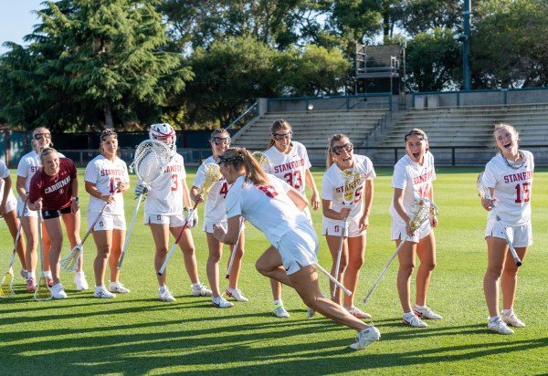 Lacrosse player runs past line of teammates.