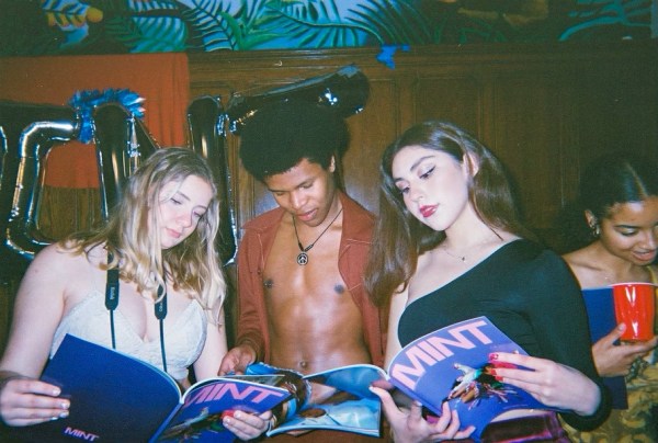 Three students gather together to read the MINT magazine in 2022.