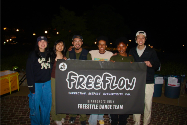 A group of dancers posed together for a photo while holding a black-and-white banner