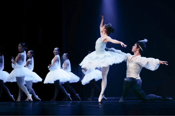 Ballet dancers wearing white perform onstage at Dinkelspiel Auditorium.