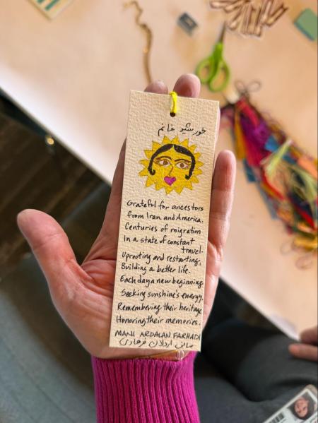 A hand-drawn bookmark with an image of a woman's face inside a sun.