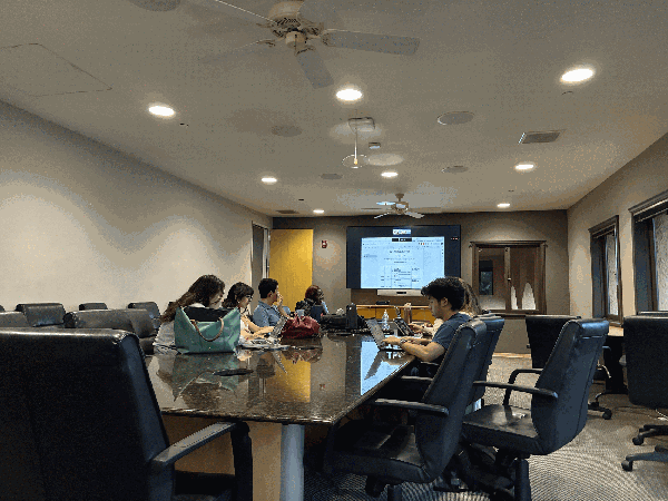 Students sit around a conference table.