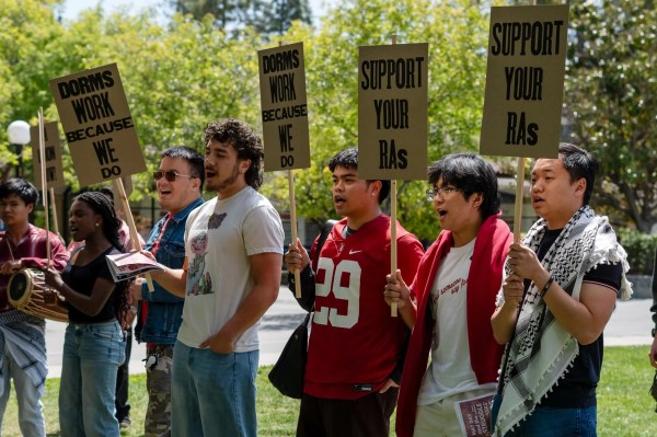 Students stand on lawn with signs to support RAs.