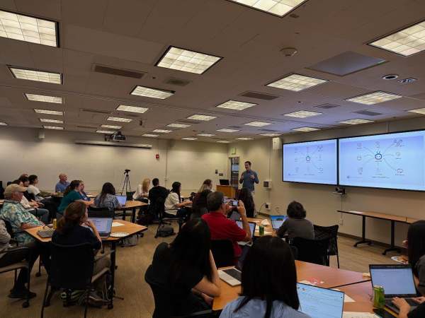 People sit in classroom facing a screen.