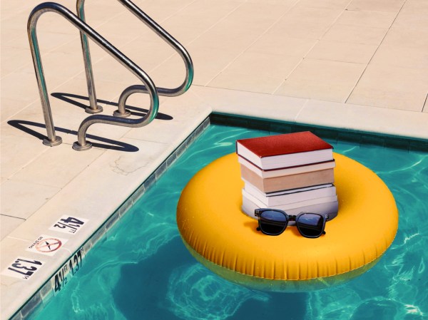 A stack of books and a pair of sunglasses floating on an inner tube in a pool
