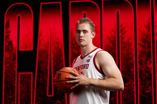 Basketball player holds ball up to his chest.