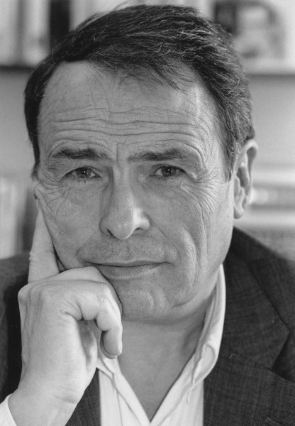 A photo of Pierre Bourdieu with his hand on his cheek looking straight into the camera.
