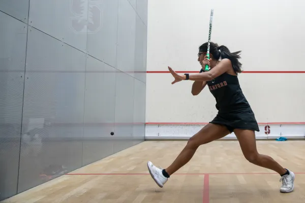 Squash player approaches to hit ball.