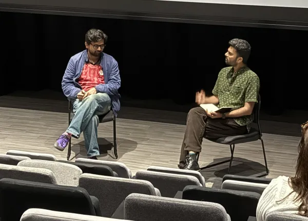 Two men sitting in front of a blank screen engaged in a Q&A session.